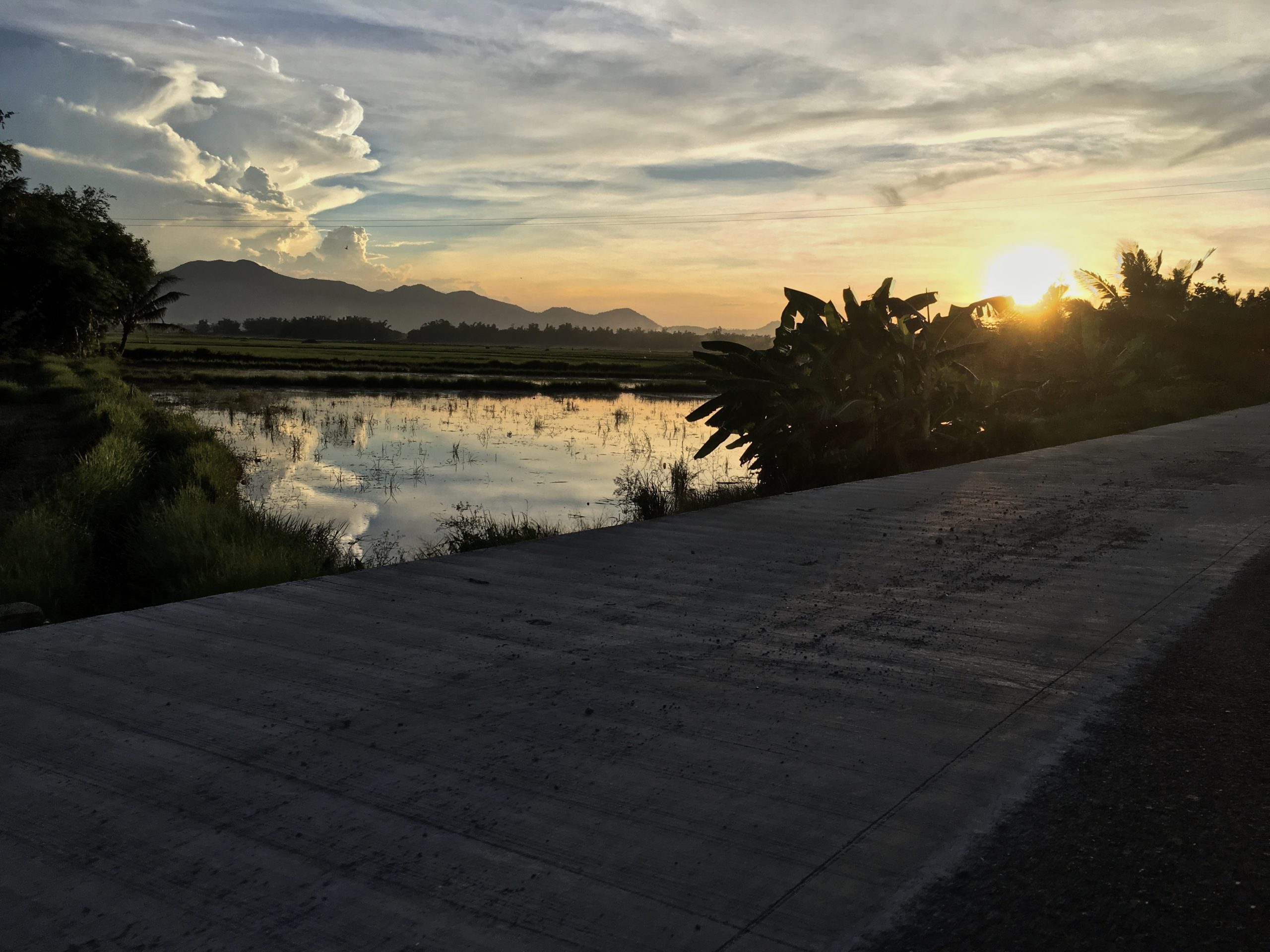 beautiful sunset and cloud reflections on the rice paddies near Balasan Philippines by Melinda J. Irvine