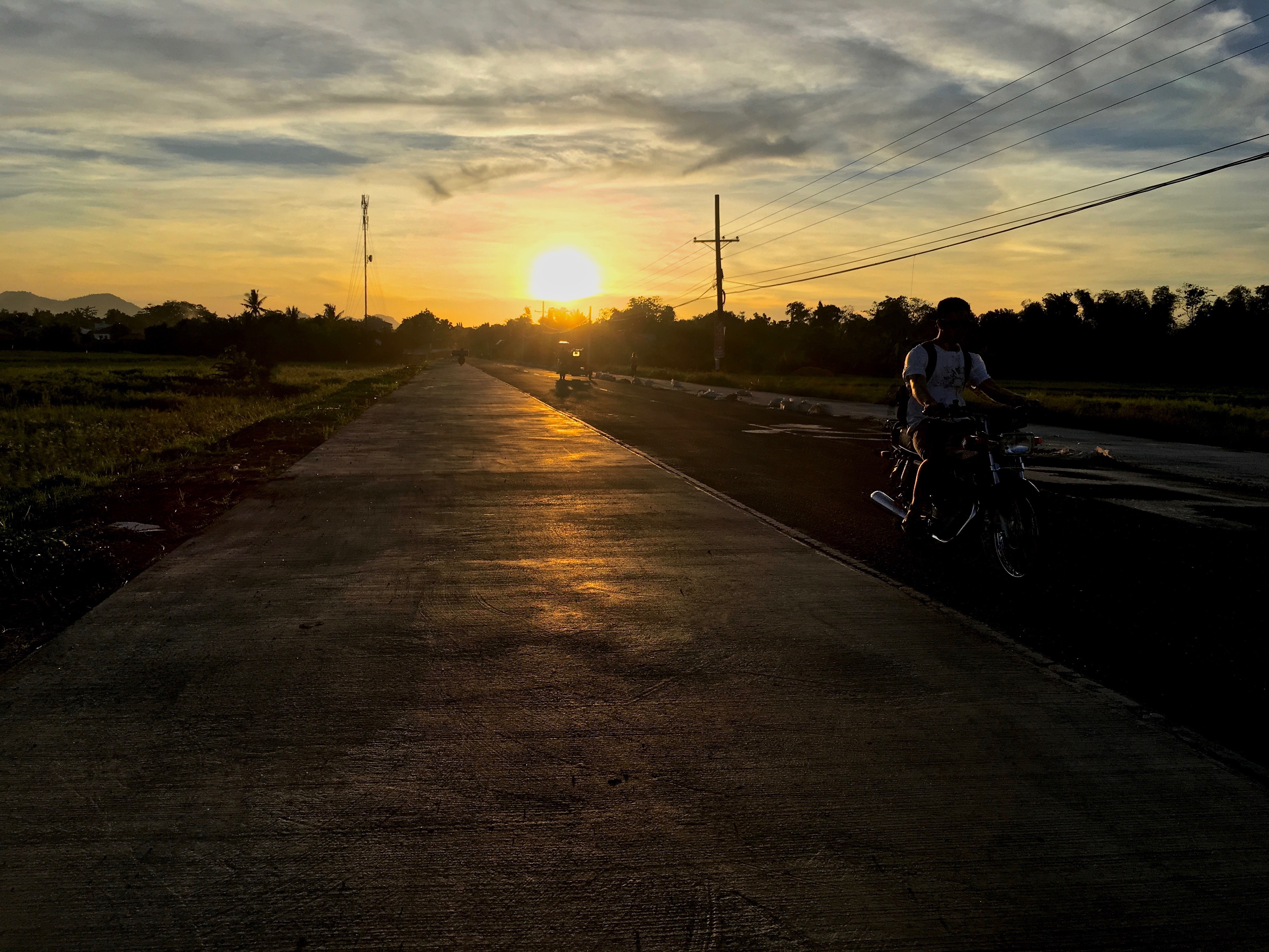 motorbikes and tricycles barely visible at sunset near Balasan Philippines by Melinda J. Irvine