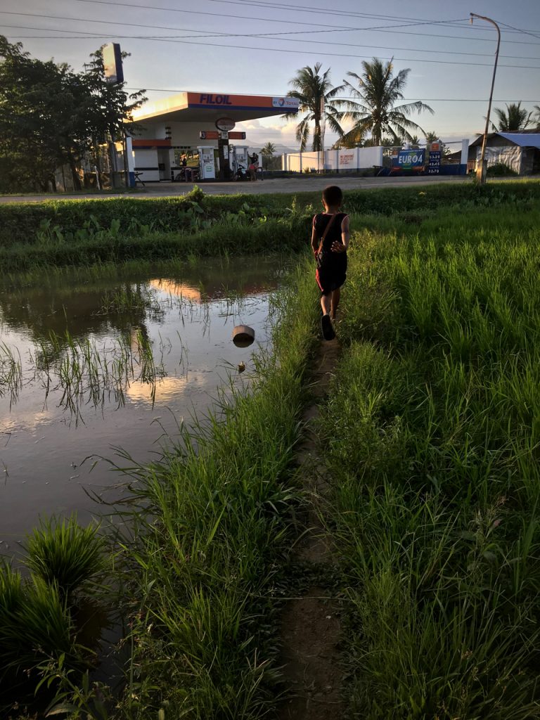 little boy running in a rice paddy