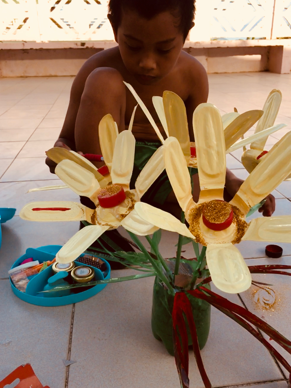 little boy painting plastic flowers